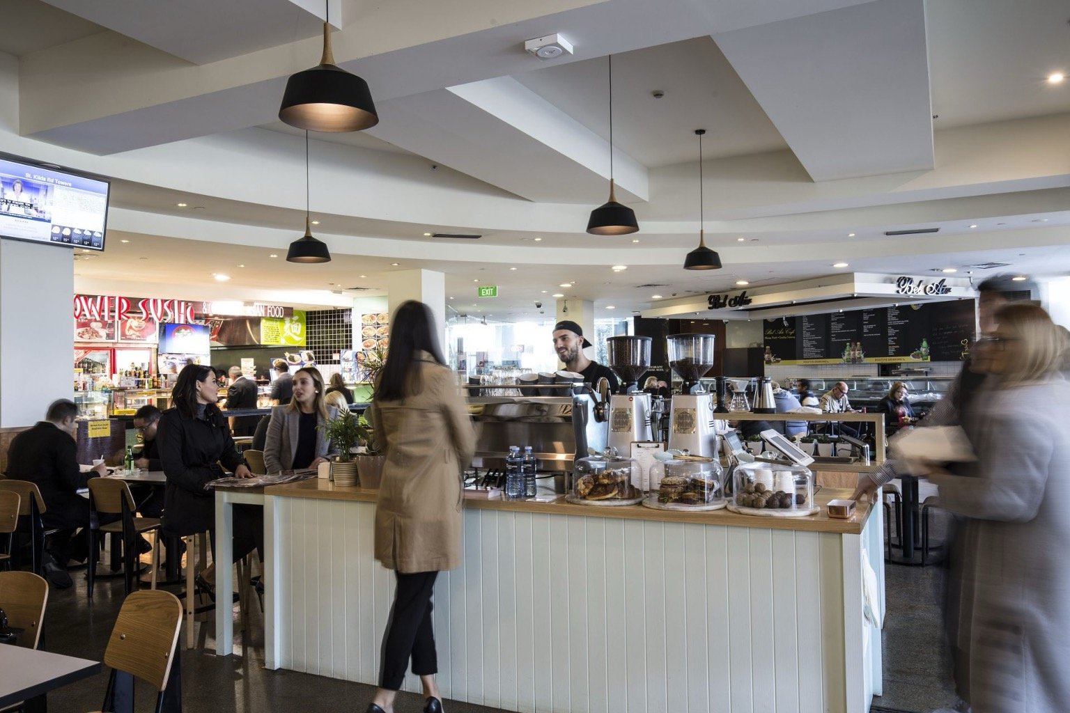 Busy food court with people ordering at a cafe counter.